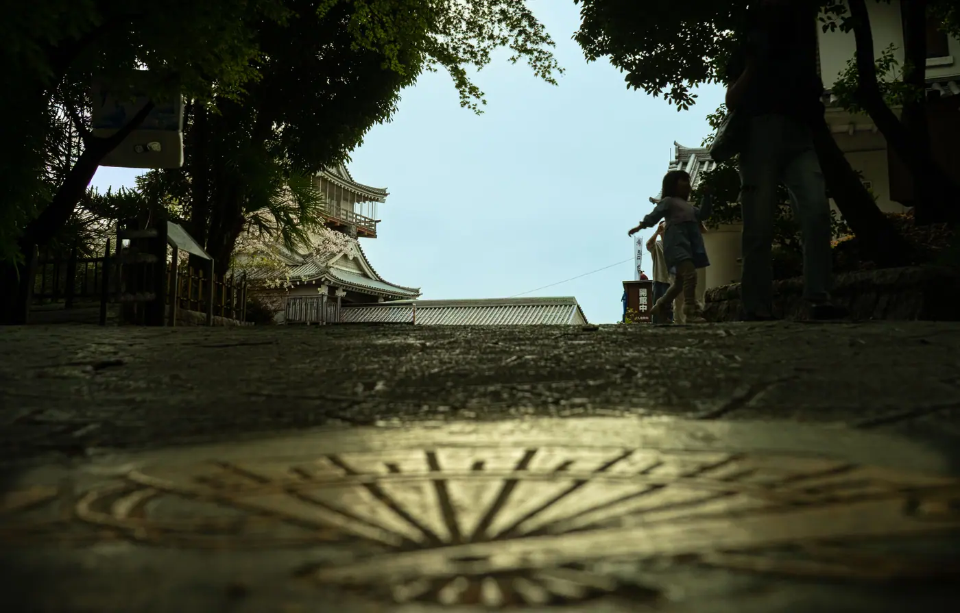 A low-angle view across a manhole cover toward Iwasaki Castle