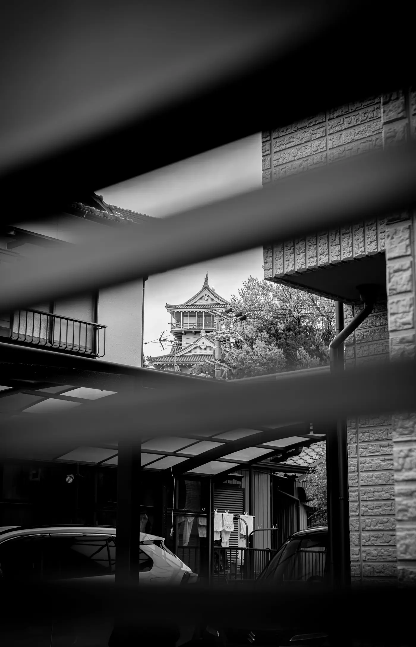 Iwasaki Castle glimpsed between neighborhood buildings, in black and white