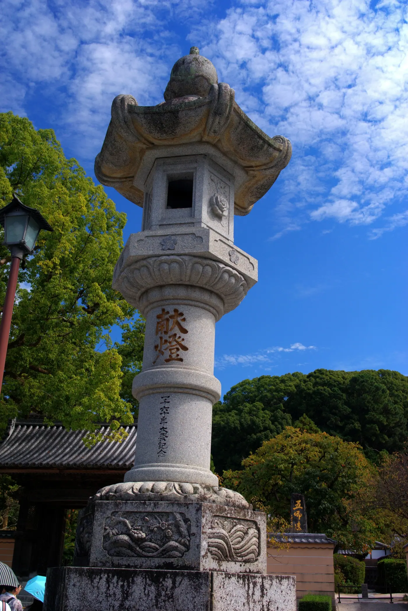 A tall stone lantern under a blue sky at Dazaifu Tenmangu