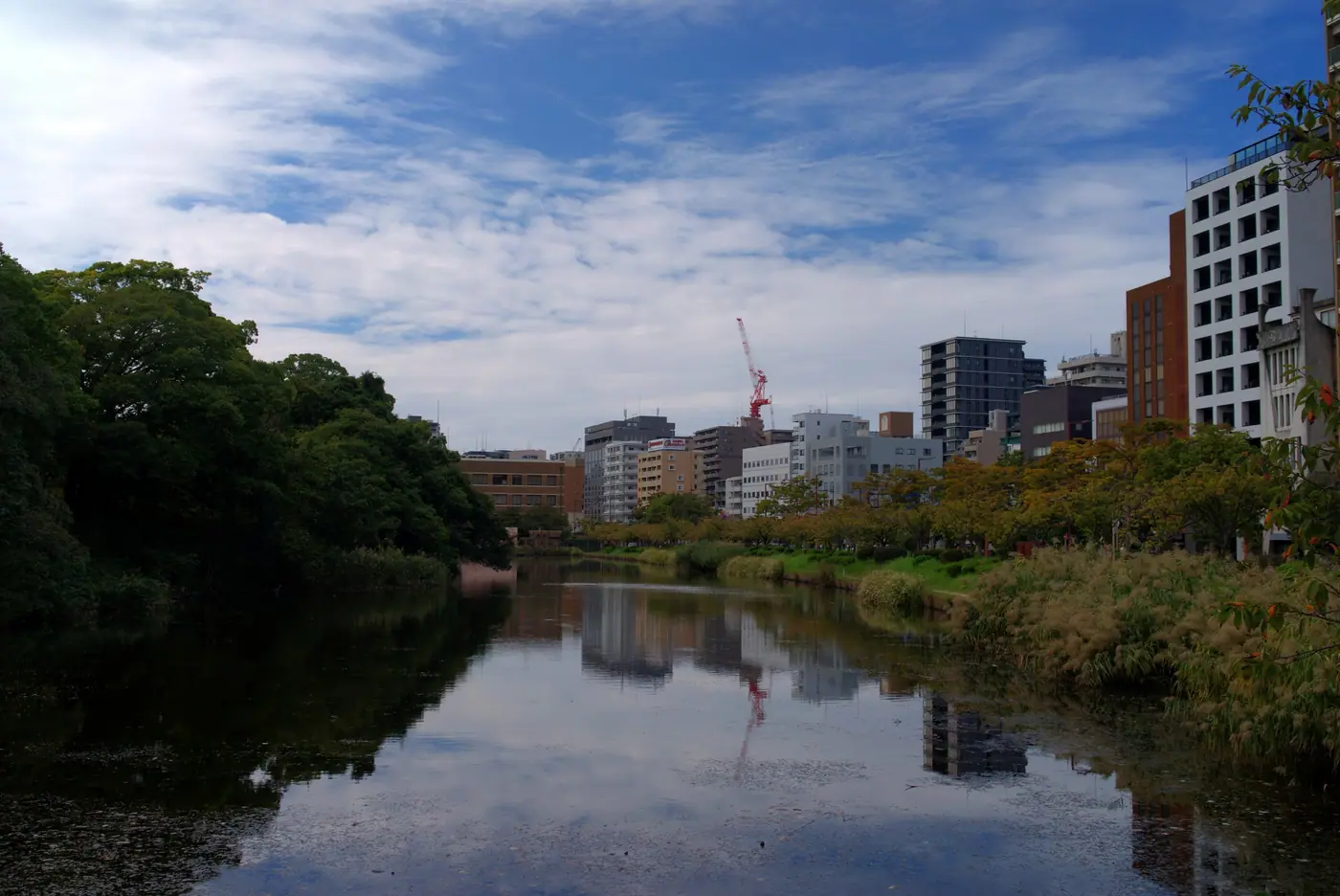 The castle moat reflecting city buildings at Fukuoka Castle Ruins