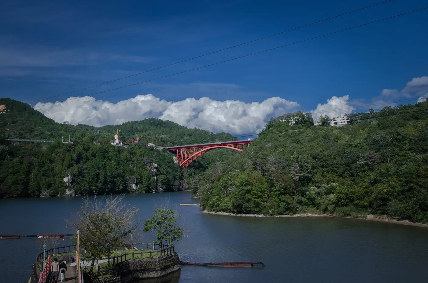 A red bridge across the lake at Enakyo, Ena Gorge, under blue sky