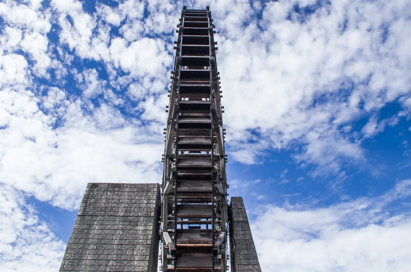 Looking up at the waterwheel against a cloudy blue sky