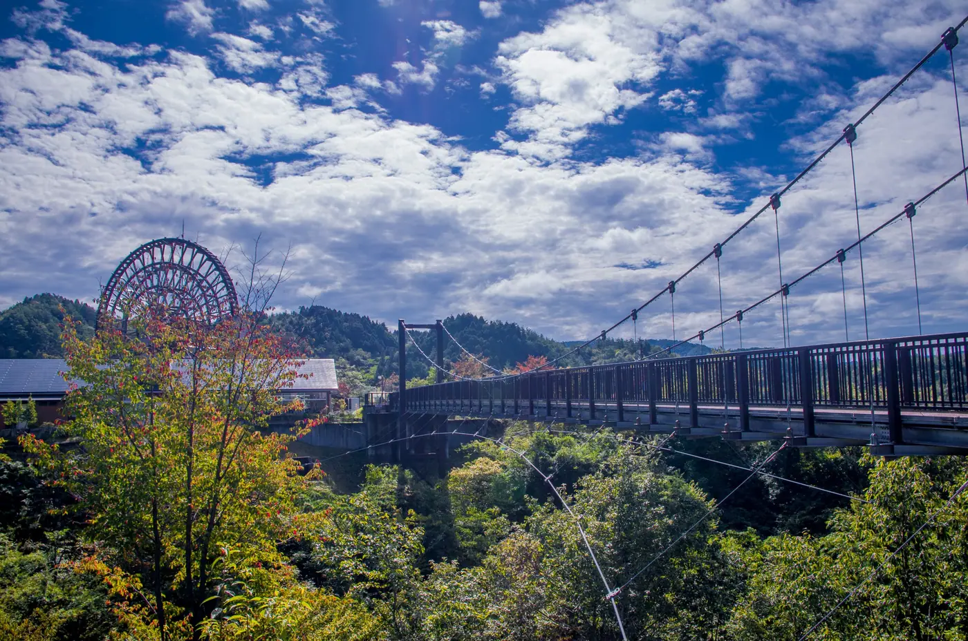 The suspension bridge at Obaachan-ichi Yamaoka with the waterwheel and valley behind it